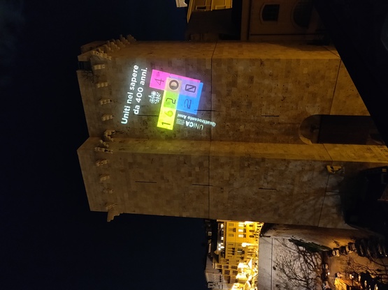 Il logo ideato da Stefano Asili per i 400 anni di UniCa proiettato sulla Torre dell'Elefante